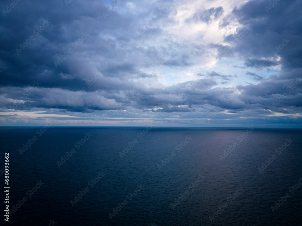 A bird's-eye view of a dark sea, horizon, and dramatic sky before a storm in the evening