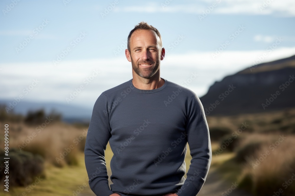 Portrait of a grinning man in his 40s showing off a thermal merino wool top against a quiet countryside landscape. AI Generation Portrait of a grinning man in his 40s showing off a thermal merino wool top against a quiet countryside landscape. AI Generation