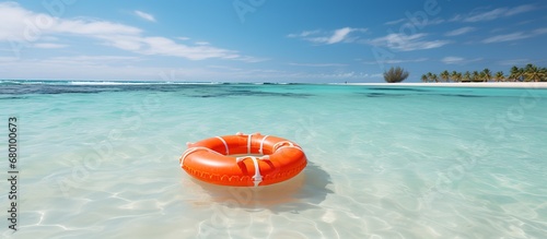 Orange lifebuoy floating in the shallow water of a tropical beach