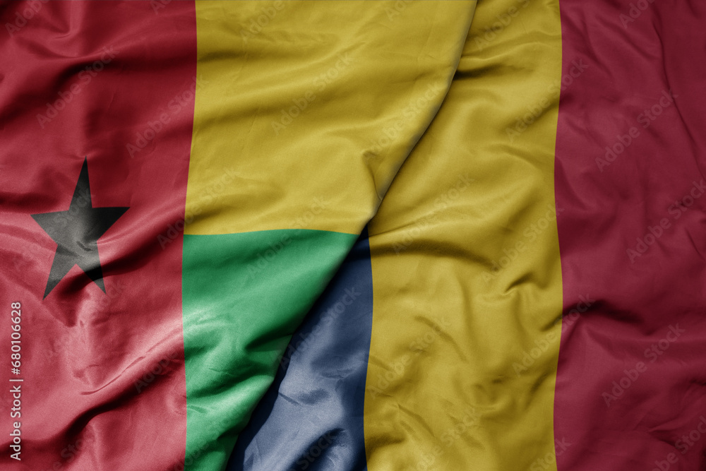 big waving national colorful flag of chad and national flag of guinea bissau .