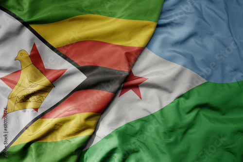 big waving national colorful flag of djibouti and national flag of zimbabwe .