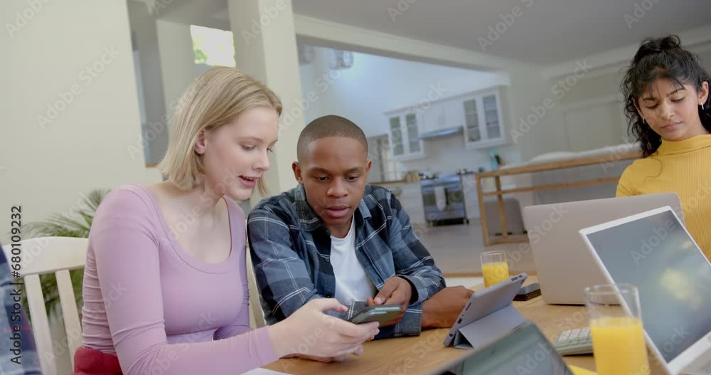 Diverse group of teenage friends studying at table with tablets and smartphone at home, slow motion Diverse group of teenage friends studying at table with tablets and smartphone at home, slow motion