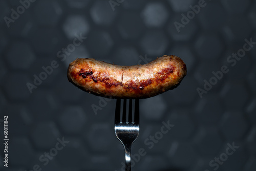 fried sausage on a fork on a dark background. food photo