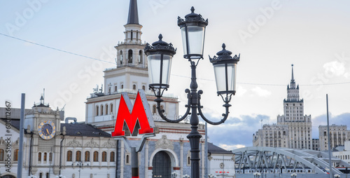Moscow metro sign and Stalinist architecture on background. Selective focus on metro sign. photo