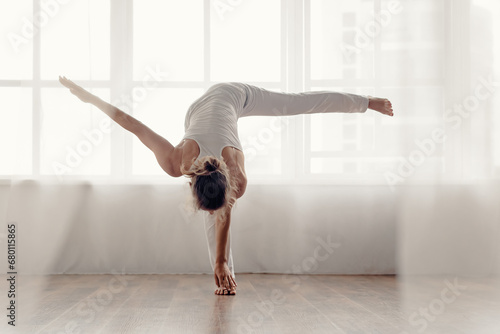 Young athletic woman practicing yoga with big light window on the background, Captivating image of a slender woman in sportswear engaged in yoga practice.