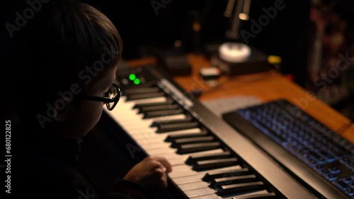 Little kid plays a keys (synthesizer , electric piano or keyboard) at home. Incorrectly plays with one finger. A child's interest in music is the first steps. Soft focus.