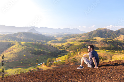 A man sitting on top of the mountain  contemplating the mountainous landscape. A moment of reflection and inspiration.