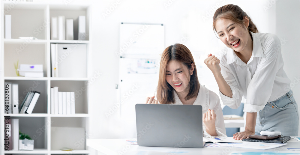 Two young excited confident Asian business woman winner raising hands celebrating career financial success at office. Two young excited confident Asian business woman winner raising hands celebrating career financial success at office.