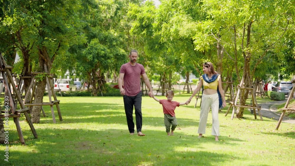 Cute Caucasian boy is playing with father and mother in village grass. Father mustache and mother is beautiful. Children walk hand in hand and threw son forward. at the park Family holiday concept Cute Caucasian boy is playing with father and mother in village grass. Father mustache and mother is beautiful. Children walk hand in hand and threw son forward. at the park Family holiday concept