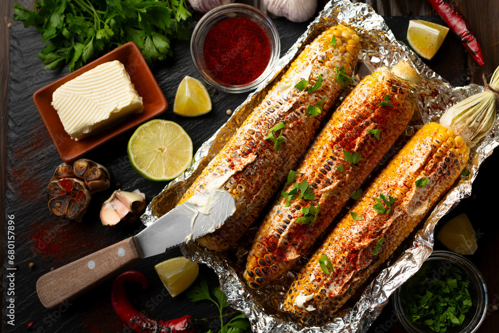 Grilled Sweetcorn with smoked paprika lime and butter in tin foil on kitchen table healthy gluten free food background
