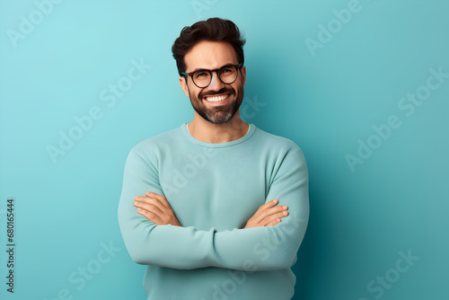 Happy bearded man in blue, smiling, arms crossed, indoor studio