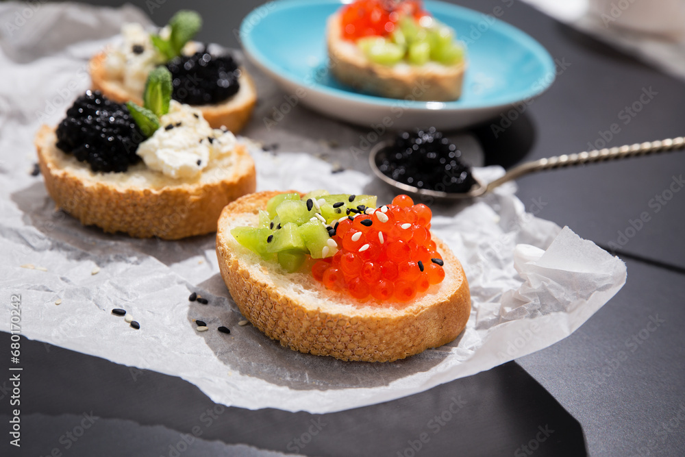 Fusion cuisine concept. Fine dining with caviar appetizer. Fine dining with caviar appetizer, red and black caviar canape of white crispy baguette bread with chopped kiwi fruit and sezame seeds. Fusion cuisine concept. Fine dining with caviar appetizer. Fine dining with caviar appetizer, red and black caviar canape of white crispy baguette bread with chopped kiwi fruit and sezame seeds.