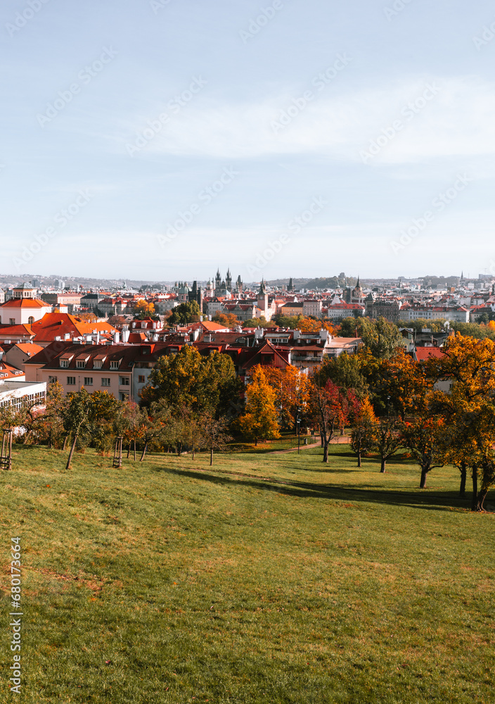 Beautiful park in Prague (Large Strahov garden) with colorful yellow-orange trees and amazing  view of city on background during the warm autumn day.