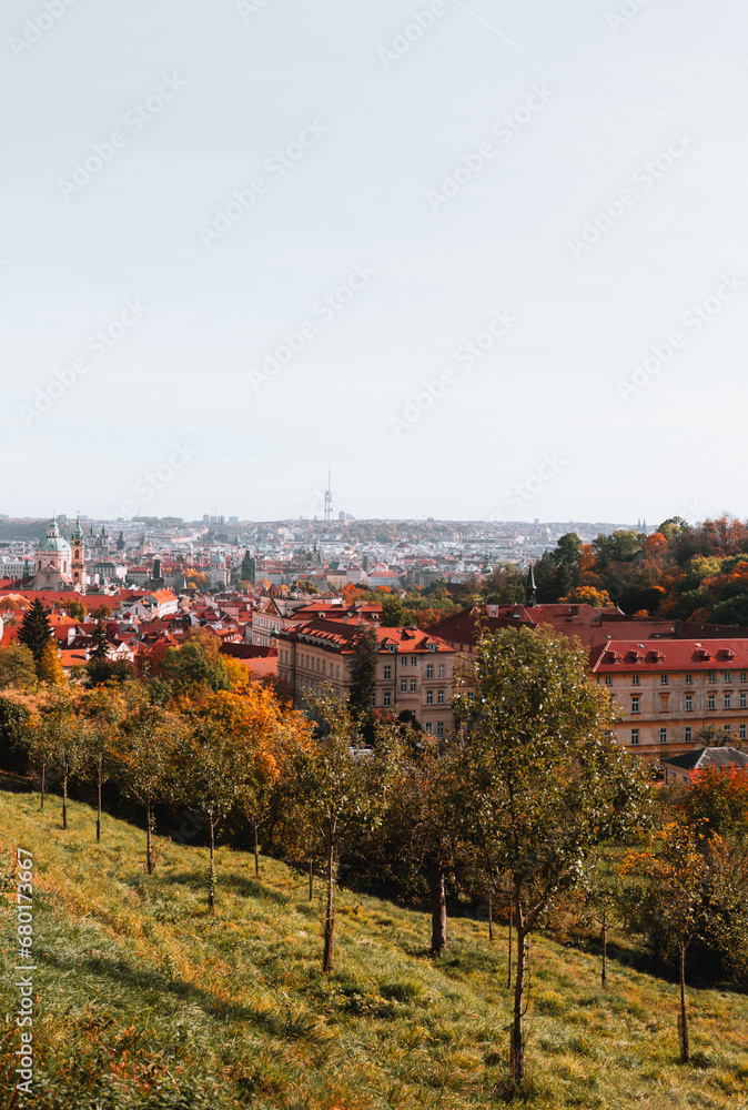 Beautiful park in Prague (Large Strahov garden) with colorful yellow-orange trees and amazing  view of city on background during the warm autumn day.