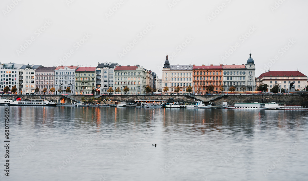 Wide-angle shot of historical part of Prague with Vltava River on foreground - taken at evening.