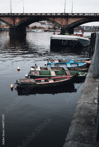 Photo of boats on the Vltava river in Prague Czechia at the evening. Colorful vessels on the river in city - dark urban photo.
