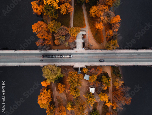 Top view shot of bridge (road) over the colorful Strelecky Island with beautiful yellow trees in Prague Czechia - autumn season. Road with cars and colorful forest during the fall in Prague city. photo