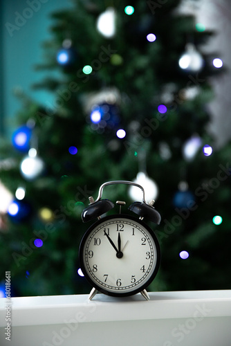 The New Year's clock against the background of the Christmas tree shows 23.55, five minutes before the New Year