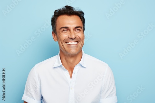 Portrait of a jovial man in his 40s wearing a classic white shirt against a pastel blue background. AI Generation © CogniLens