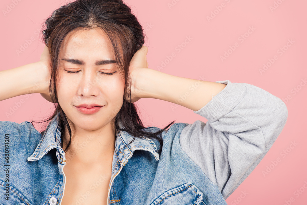 Asian portrait beautiful cute young woman wear denim have closed ears with hand palms and close eyes, studio shot isolated on pink background, Thai female covers ears for loud noise with copy space Asian portrait beautiful cute young woman wear denim have closed ears with hand palms and close eyes, studio shot isolated on pink background, Thai female covers ears for loud noise with copy space