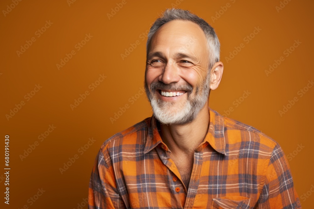 Portrait of a grinning man in his 50s dressed in a relaxed flannel shirt against a pastel orange background. AI Generation Portrait of a grinning man in his 50s dressed in a relaxed flannel shirt against a pastel orange background. AI Generation
