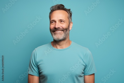 Wallpaper Mural Portrait of a happy man in his 40s sporting a vintage band t-shirt against a pastel teal background. AI Generation Torontodigital.ca