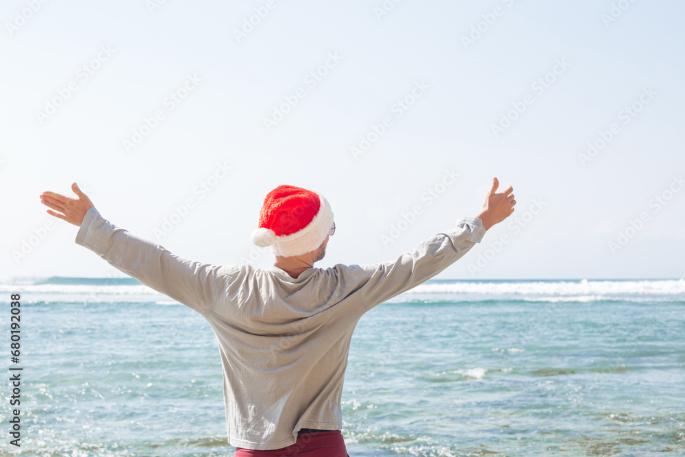 Joyful man in Christmas hat on ocean shore concept celebrating new year by the sea Joyful man in Christmas hat on ocean shore concept celebrating new year by the sea