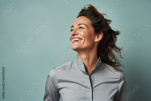 Portrait of a blissful woman in her 30s sporting a technical climbing shirt against a pastel gray background. AI Generation