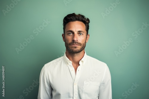 Portrait of a tender man in his 30s wearing a classic white shirt against a soft teal background. AI Generation