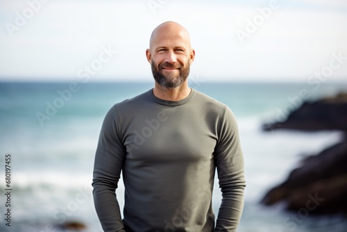 Portrait of a happy man in his 40s showing off a thermal merino wool top against a serene seaside background. AI Generation