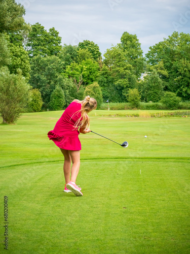 Blonde Woman in red dress play Golf on Bavarian green grass