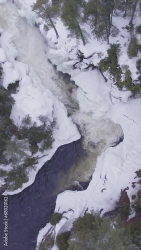 Aerial view of white winter landscape with a frozen river in the mountains with  flowing water in East Canada (ID: 680201624)