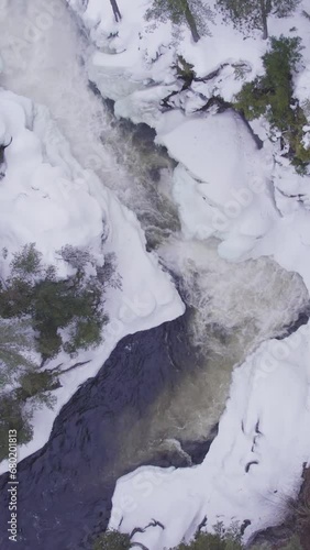 Aerial view of white winter landscape with a frozen river in the mountains with  flowing water in Canada (ID: 680201813)