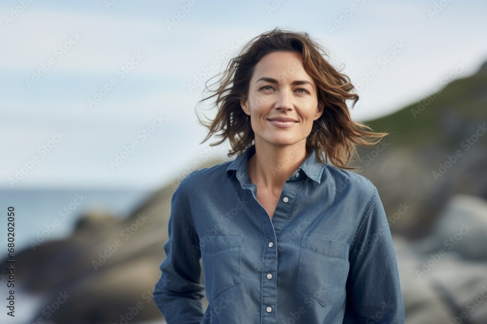 Portrait of a glad woman in her 40s sporting a versatile denim shirt against a rocky shoreline background. AI Generation Portrait of a glad woman in her 40s sporting a versatile denim shirt against a rocky shoreline background. AI Generation