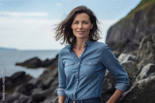 Portrait of a glad woman in her 40s sporting a versatile denim shirt against a rocky shoreline background. AI Generation