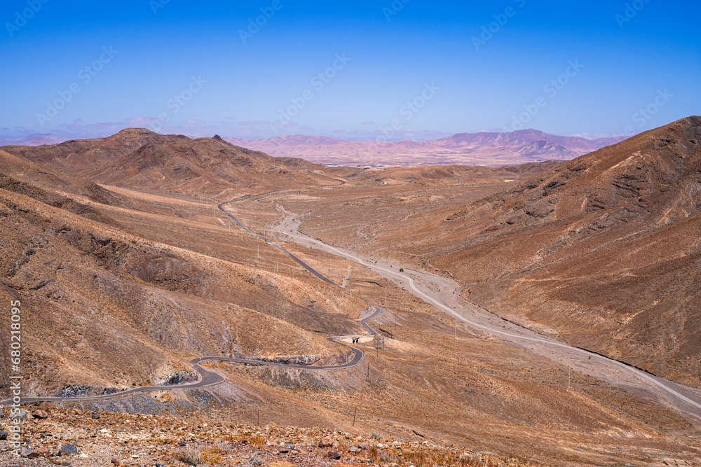 View of a completely dry and desert valley where a small road runs. Photography taken in Fuerteventura, Canary Islands, Spain.