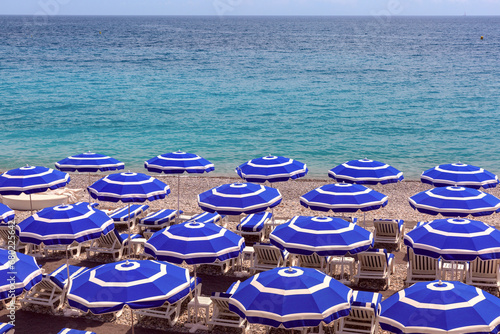 Parasols on beach of Nice in sunny summer day with blue sky, Nice, French Riviera, France