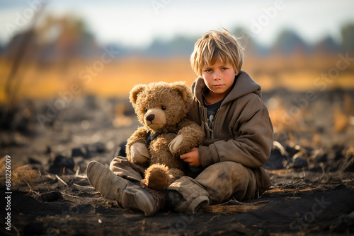 A young boy with a teddy bear sits outdoors, looking thoughtfully into the distance during golden hour.