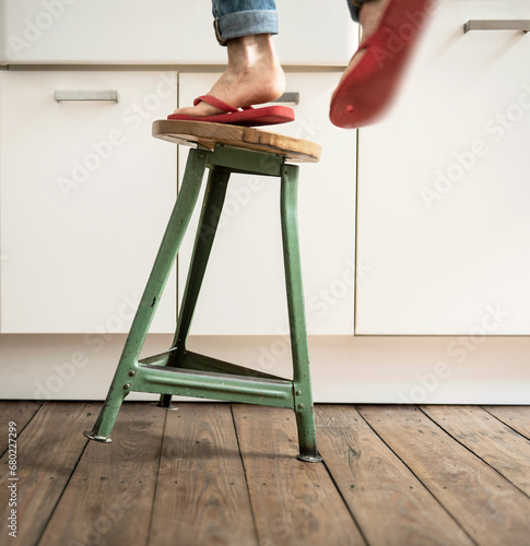 Person steht mit Flip-Flops auf einem wackeligen Hocker und fällt - Gefahren im Haushalt photo