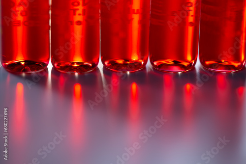 Injection ampoules of hormone B12 in selective focus. Red colored vitamin B12 liquid in injection ampoules. Background with science, biology, chemistry, medicine, health concepts.