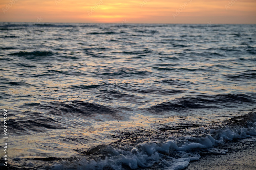 Naklejka premium Ocean sunset landscape with soft evening sea water waves crushing on sandy beach