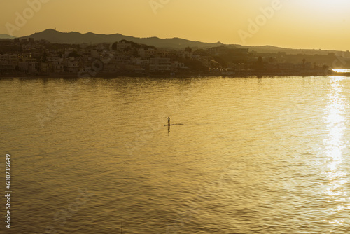 The man paddleboarding on sea early sunset