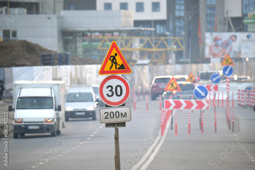 Roadworks warning traffic signs of construction work on city street and slowly moving cars photo
