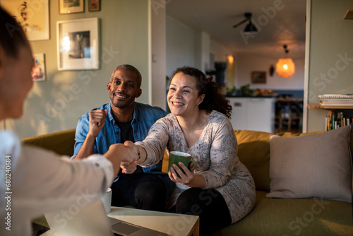 Mixed couple having a conversation with insurance saleswoman at home photo