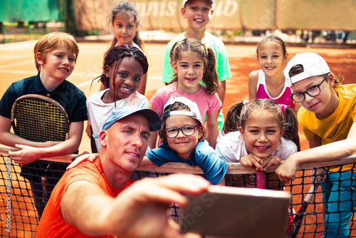 Tennis couch taking selfie with little children during practice photo