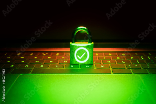 Closeup of a padlock on a laptop illuminated with green light. Phishing, cybersecurity danger or ransomware attack.The padlock is unlocked and displays a green OK checkmark.