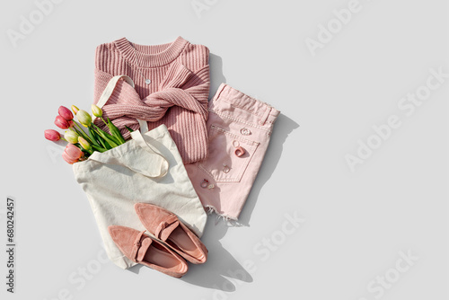 Fashion spring outfit. Pale pink jumper with bouquet of tulips flowers in bag,  jeans and loafers. Women's stylish and elegant clothes with accessory and jewelry.  Flat lay, top view, overhead. #680242457