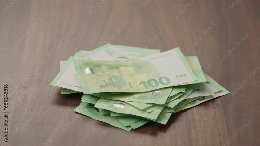 Pile stack of hundred euro bills on walnut table slide shot Pile stack of hundred euro bills on walnut table slide shot