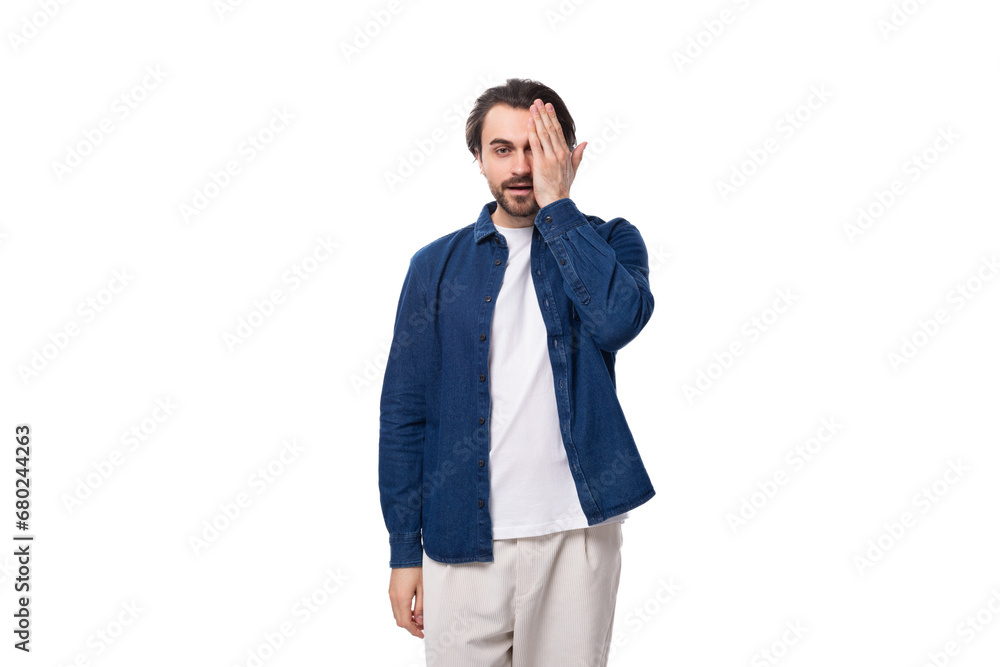 young european brunette man with a cool hairstyle is dressed in a blue denim shirt over a t-shirt young european brunette man with a cool hairstyle is dressed in a blue denim shirt over a t-shirt