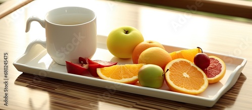 In the background of a serene holiday retreat, a white wooden tray is adorned with a colorful array of sliced fruits green apple, orange, lemon, and yellow honey drizzled on top, complemented by a photo